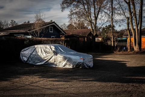 DEU Germany Germany Berlin A car, wrapped in a tarpaulin, is parked in a car park next to an