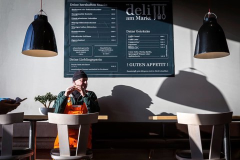 DEU Germany Germany Berlin A man eats a sandwich in a snack bar attached to the Rewe supermarket in