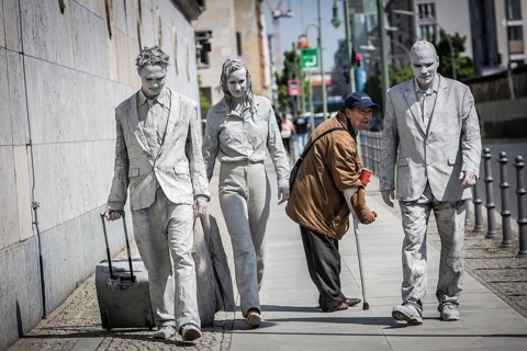 DEU Germany Germany Berlin Three people painted in grey walk along the wall of the Ministry of