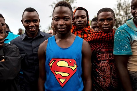 TZA TANZANIA Benaco Young people listen to a nappy salesman in a marketplace. A man in a superman