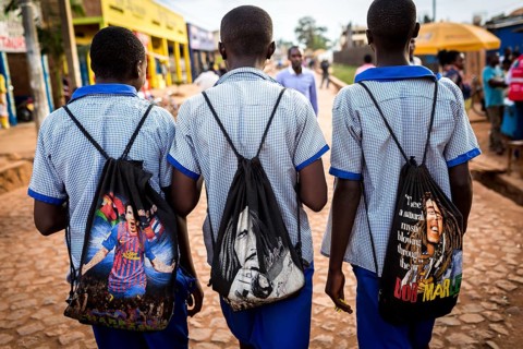 RWA RWANDA Rwanda Kayonza students in uniform carry backpacks with their idols Lionel Messi and Bob