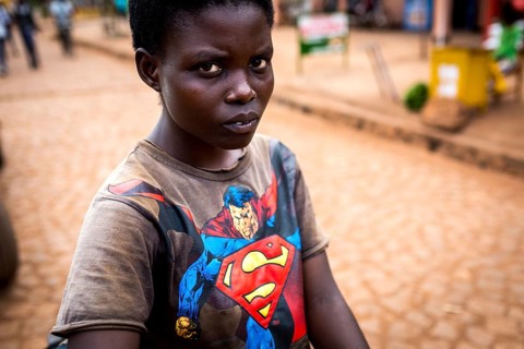 RWA RWANDA Rwanda Kayonza A young woman with a bicycle shows her Superman shirt