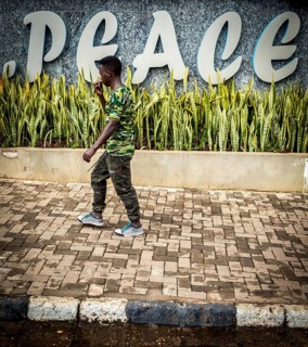 RWA RWANDA RUANDA Kigali A man in camouflage fashion passes a Peace font in the Kiyovu banking