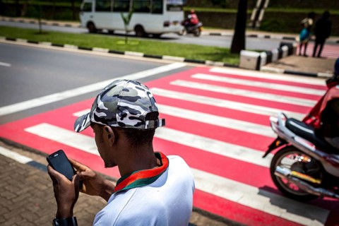 RWA RWANDA RUANDA Kigali A youth with a camouflage baseball cap looks at his mobile phone while