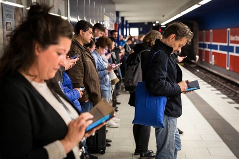 DEU Germany Germany Berlin Passengers look at their mobile phones while waiting for the train at