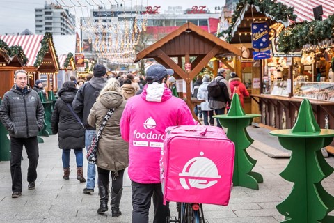 DEU Germany Germany Berlin A Foodora food courier rides his bike through the Christmas market on