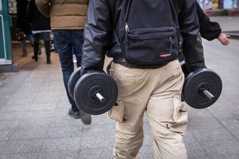 DEU Germany Germany Berlin A man carries two dumbbells in his hands on his way to the underground
