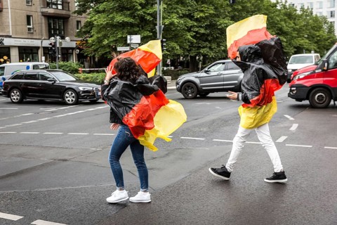 DEU Germany Germany Berlin Two tourists with rain capes in the colours of Germany while sight