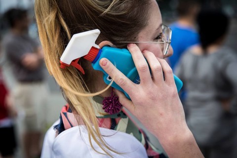 DEU Germany Germany Berlin A woman talks on her smartphone with a glass cleaner tab on the cover