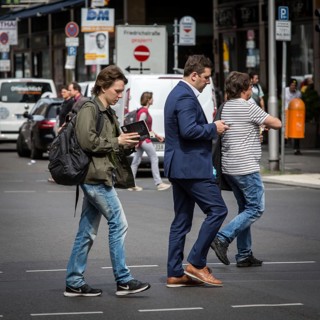 DEU Germany Germany Berlin A young man walks along Friedrichsstrasse reading while another looks at