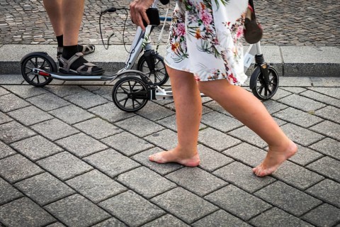 DEU Germany Germany Berlin A woman passes a family on pedal scooters barefoot on Pariser Platz in