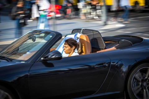 DEU Germany Germany Berlin A woman is dazzled by the sun as she drives her convertible across