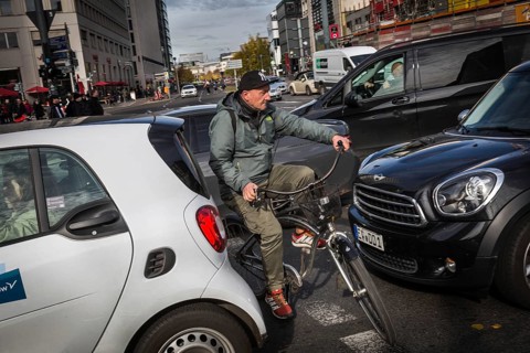DEU Germany Germany Berlin Cyclists squeeze between stationary cars on Potsdamer Platz