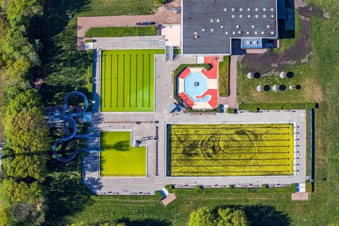 Aerial view, outdoor swimming pool south in front of the opening of the season with algae in the