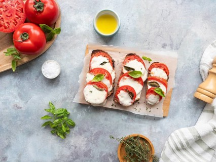 Caprese bruschetta with fresh ingredients on a light gray background, ready to eat