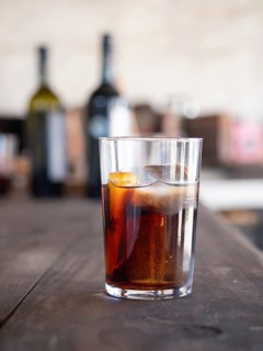Refreshing vermouth cocktail with ice and orange on a wooden table