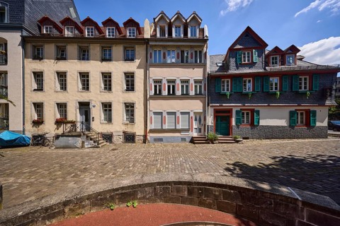 Historic buildings, houses, downpipes, façade with windows, dormers, stairs and doors, paving stone