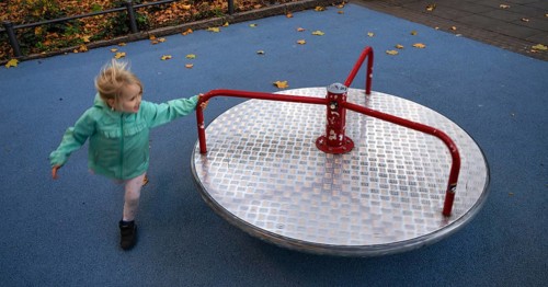 Outdoor shot, little girl, child, 4 years, blonde, playing with carousel, movement effect,