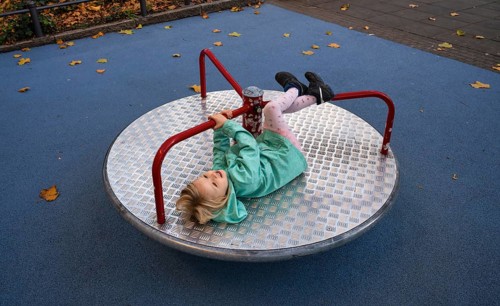 Outdoor shot, little girl, child, 4 years, blonde, playing on carousel, children's playground,