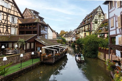 Traditional houses along a river, here called the little Venice, with tourists visiting Colmar on a