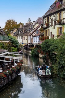 Traditional houses along a river, here called the little Venice, with tourists visiting Colmar on a