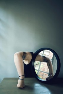 Portrait of a woman with a mirror, interior view, arm in front of the mirror, head covered