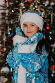 Young girl dressed as snegurochka smiling in front of a decorated christmas tree.Belarus