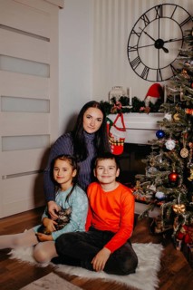 Family group portrait showing a mother, children, and kitten in a festive christmas home setting
