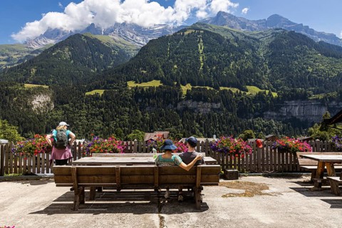 A couple sitting on a bench is enjoying the view on the mountains in Champery, a village in