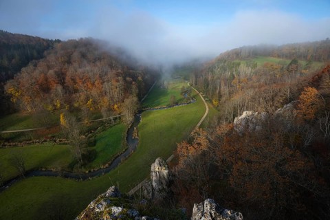 Autumn landscape with rising fog over the Grosse Lauter river loop in Lautertal at sunrise. View