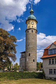 Historic tower with clock under blue sky and clouds, surrounded by buildings, The Niedeck Ruins in
