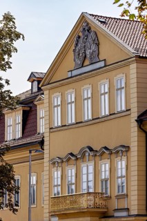 Detailed view of a baroque building with yellow façade, decorated pediment and windows, the façade