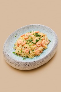 A creamy dish of risoni pasta combined with tender shrimp and fresh herbs is presented in an