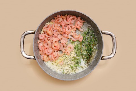 Shrimps and herbs sizzle in a pan, blending with chopped garlic, ginger and olive oil. Process of