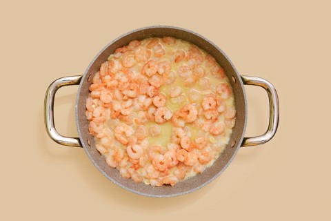 A skillet is filled with juicy, cooked shrimp in a creamy garlic sauce, ready to be tossed with