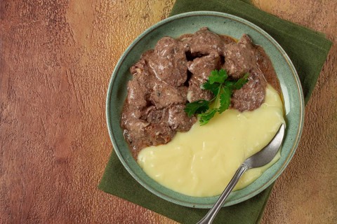 Liver beef stroganoff with mashed potatoes, table setting in green tones, homemade