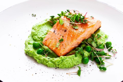 Delicious grilled salmon is placed elegantly on creamy green pea puree. Fresh microgreens and peas