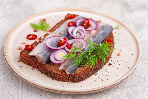 Sandwiches, Herring fish, on dark rye bread, sprinkled with onion, chili pepper and herbs, on a