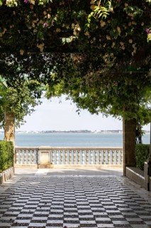 Beautiful natural park with views of the sea through pink bougainvillea. The ornamental pond in