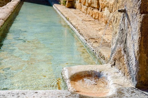 Ronda, malaga, spain Fresh, clear water flowing from an old stone spout into a historic rustic