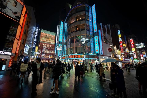 Busy pedestrian zone with many shopping centers and stores, illuminated with lots of neon signs at