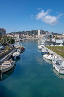 View from Pont des Dockers across the Canal de la Peyrade with moored boats along the quays towards