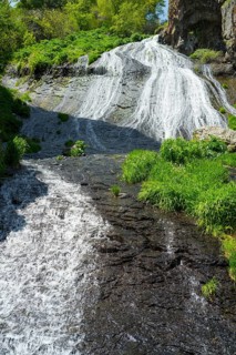 A steep stream flows through rocks and green plants, in the heart of a natural landscape, Jermuk