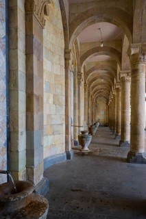Long portico with stone arches and jugs that offer a perspective into the depths and reflect a