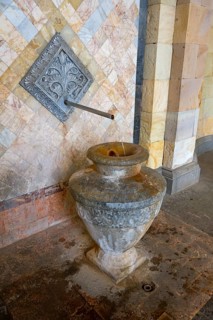 Close-up of an ancient well with mosaic decoration and detailed relief elements in stone