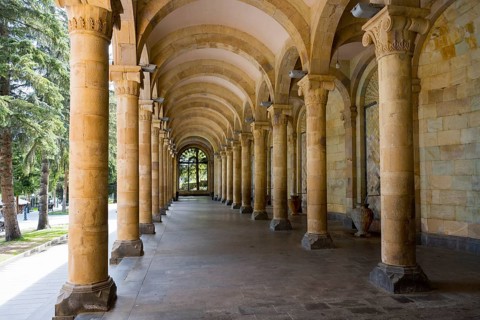 Long, minimalist portico with symmetrical stone arches in a cool interior steeped in history,