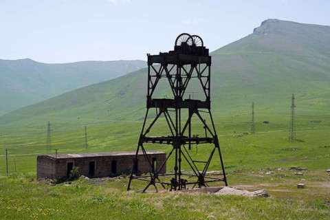An abandoned structure in a green mountain landscape with ruined buildings and power poles, disused