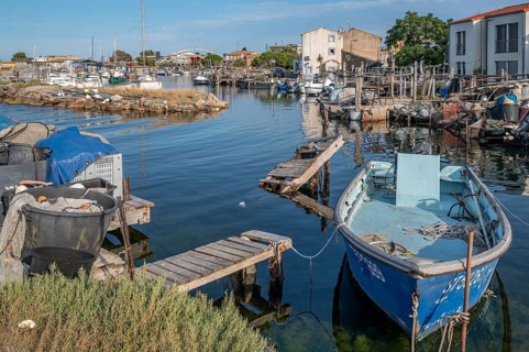 A blue fishing boat is moored on dilapidated wooden walkways in a small harbor basin of La Pointe