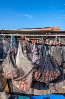 Close-up of various fishing nets and fish traps with red floats and shackles suspended for drying