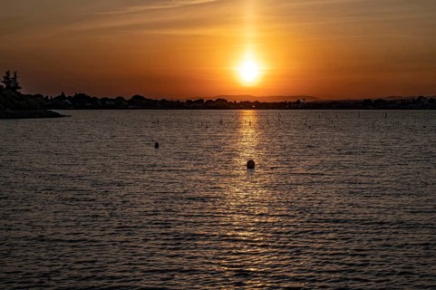 A golden sunset over the Etang de Thau with strong light reflection on the water surface, the